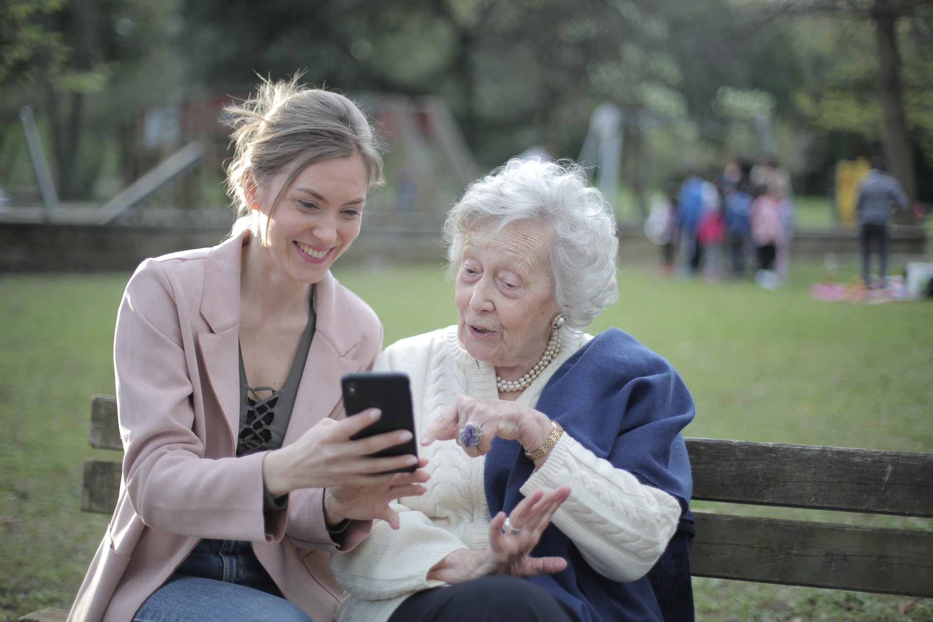 Younger woman showing older woman something on a cell phone