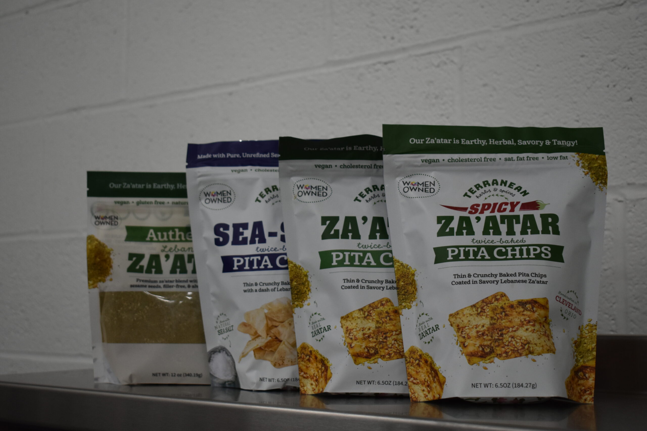 Spicy za'atar pita chips, za'atar pita chips, and sea salt pita chips on a shelf alongside a package of Terranean's za'atar spice blend